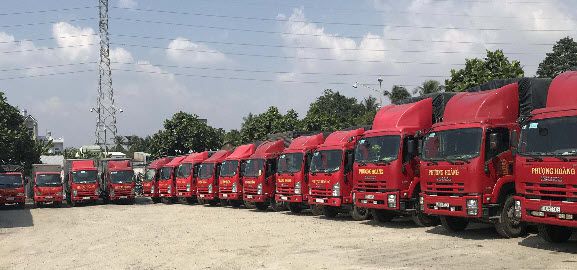 Moving truck (modern, clean) navigating a narrow, winding alley in Hanoi, challenging but efficient. Showing a smaller sized truck.