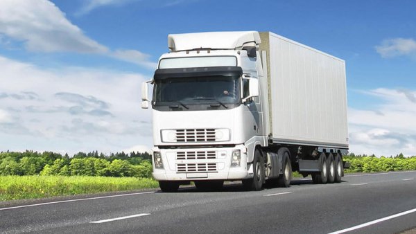 A Kiến Vàng moving company crew member expertly wrapping a delicate antique wooden cabinet with bubble wrap and stretch film inside a home's living room, surrounded by packed boxes, ensuring maximum protection for valuable items before transportation.